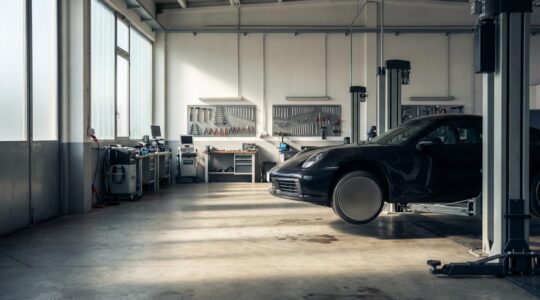 Vue d'ensemble d'une voiture sportive dans un atelier mécanique professionnel avec outils et équipements visibles